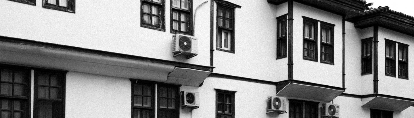 Außengerät einer Split-Klimaanlage an einer hellen Hauswand vor freiem Himmel