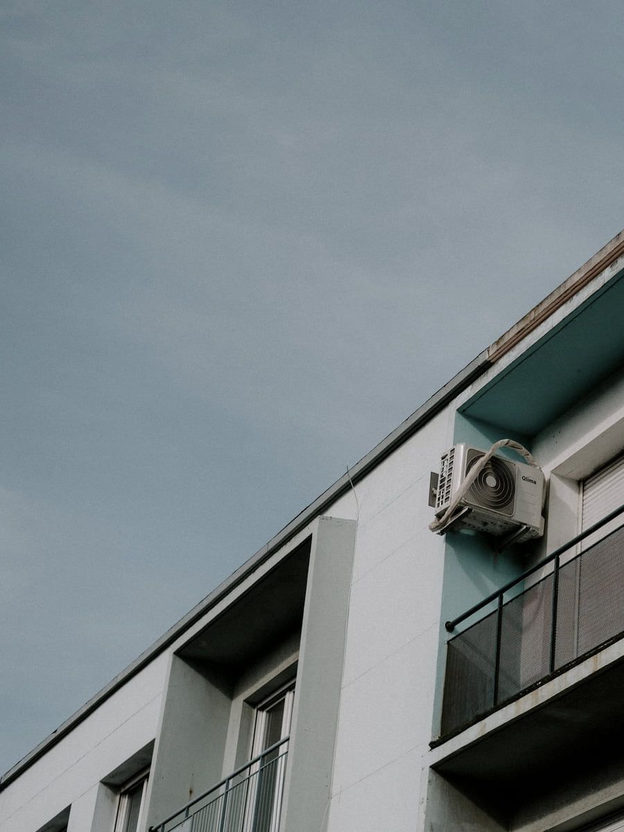 Klimaaußengerät auf einem Balkon neben der Brüstung eines Wohnhauses